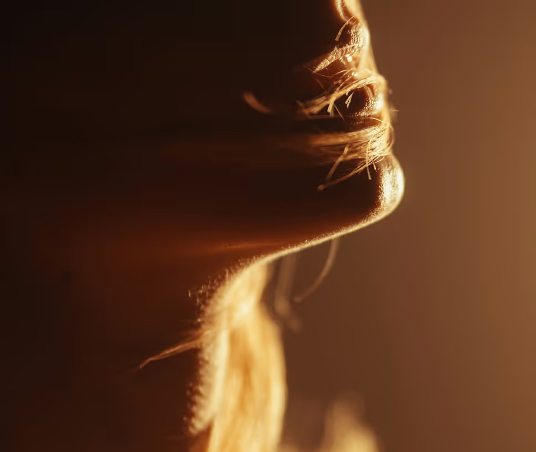 Een gezicht in profiel in warm amberkleurig licht